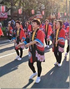 生き生きと笑顔で踊る赤い法被を着た女性たちの写真